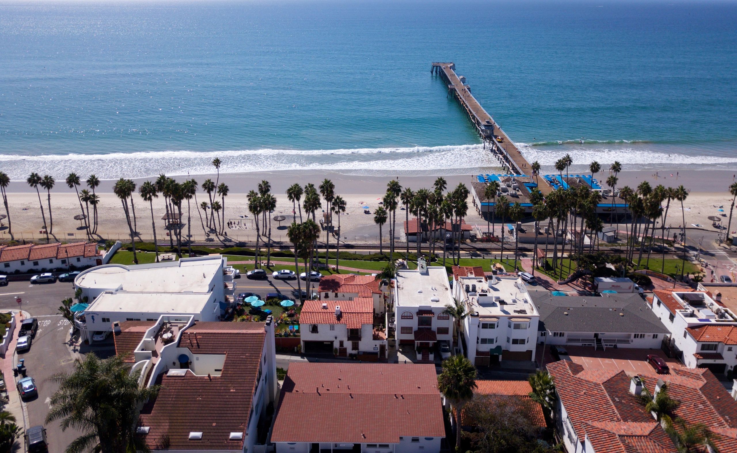 A view of the ocean from above shows houses and pier.